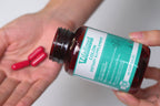 Bottle of dietary supplement with capsules on a hand against a white background