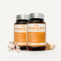 Two amber supplement bottles labeled Vitalimed Stomach Plus, shown on a light neutral background with pink flowers, a small pile of powder, and a banana slice as styling props.